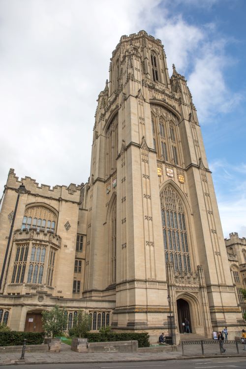 The University of Bristol Law School's Wills Memorial Building seen from street level, against a blue sky with white clouds.